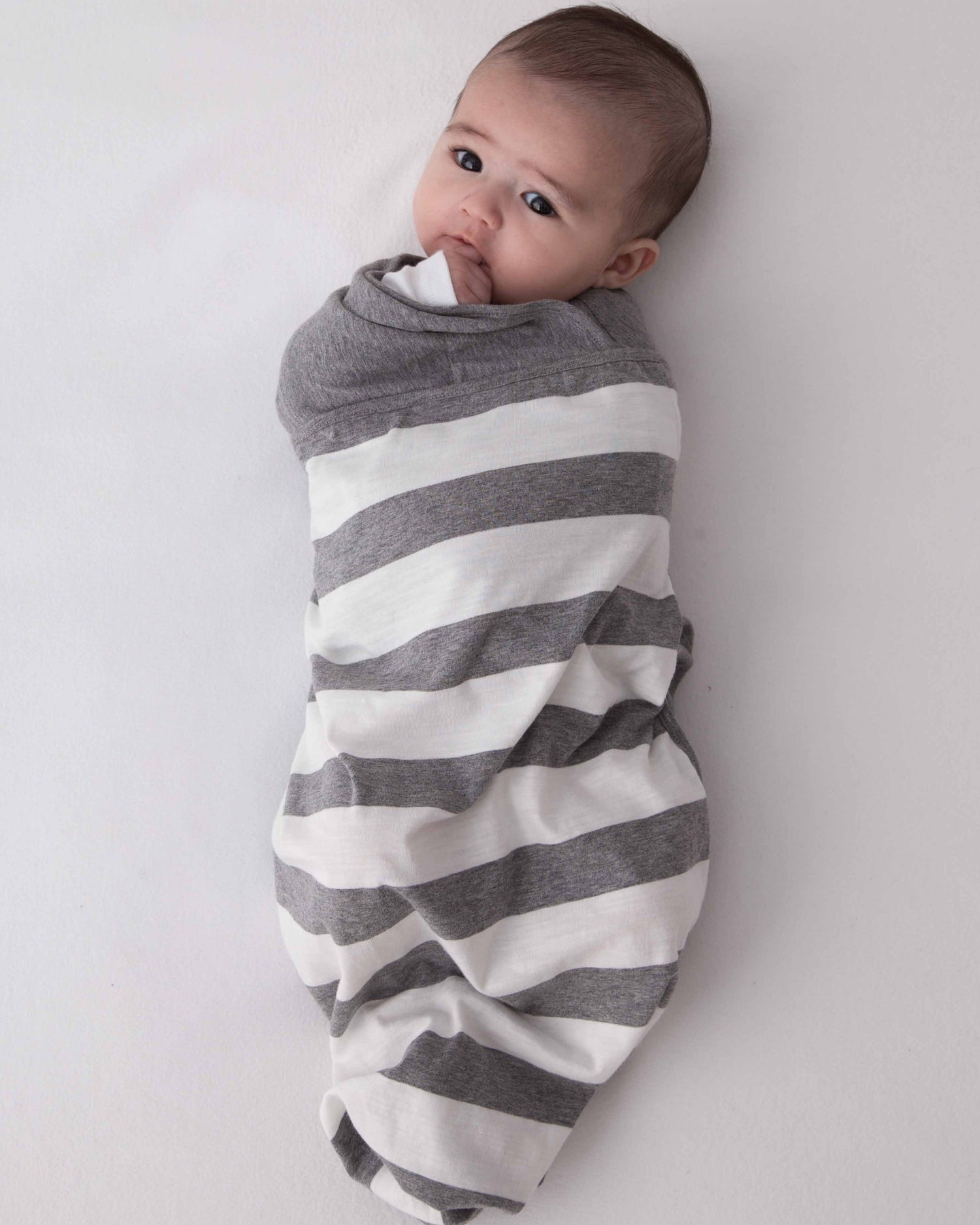 Baby wearing Swado Organic Cotton adjustable swaddle in Classic Stripe.
