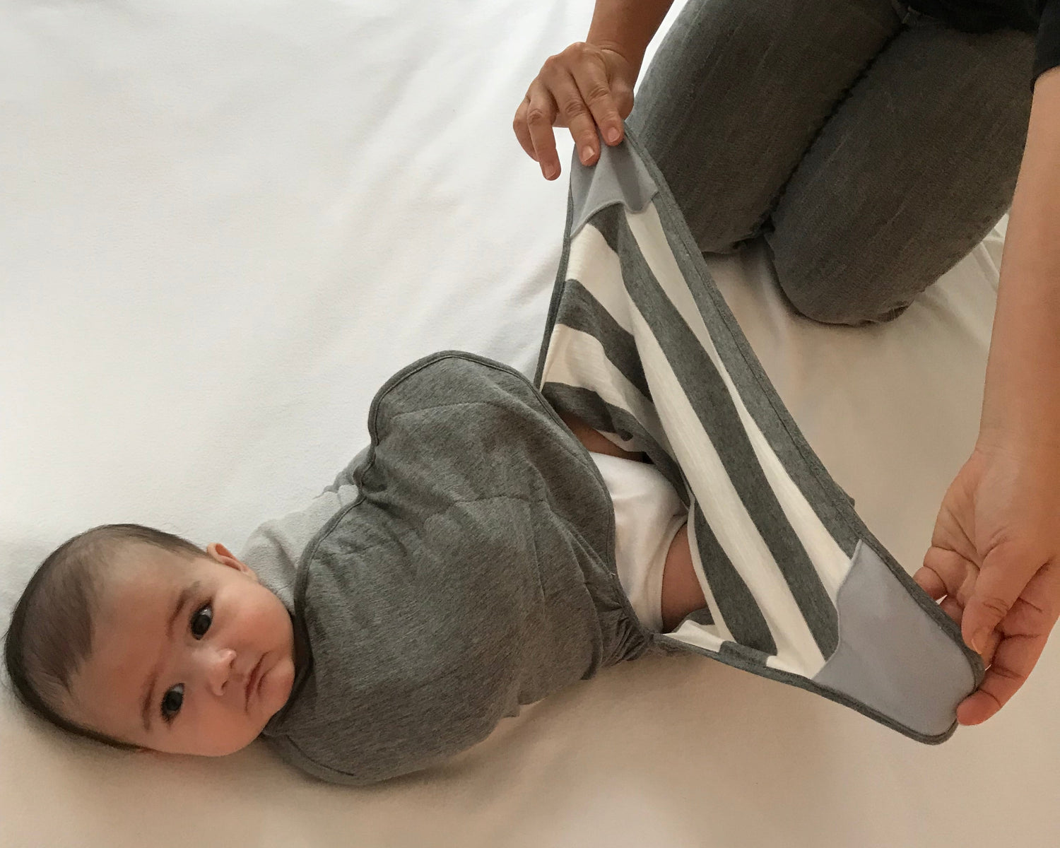 Baby wearing Swado Organic Cotton adjustable swaddle with foot pouch open for a diaper change.
