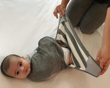 Baby wearing Swado Organic Cotton adjustable swaddle with foot pouch open for a diaper change.